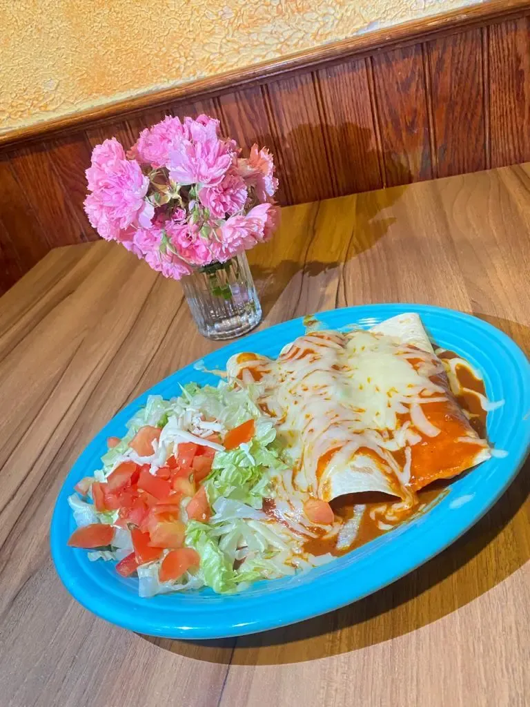 Two authentic cheese enchiladas topped with red sauce and melted cheese, plated with rice and beans